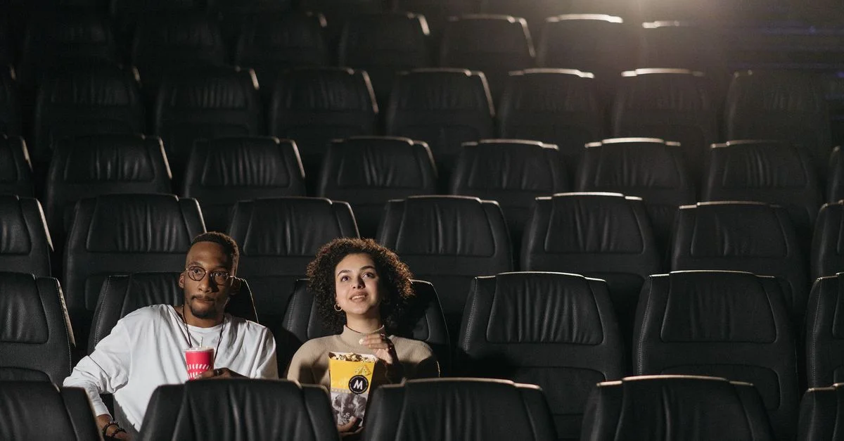 Un couple profitant de boissons et de collations lors d'une soirée cinéma dans une salle de cinéma vide.