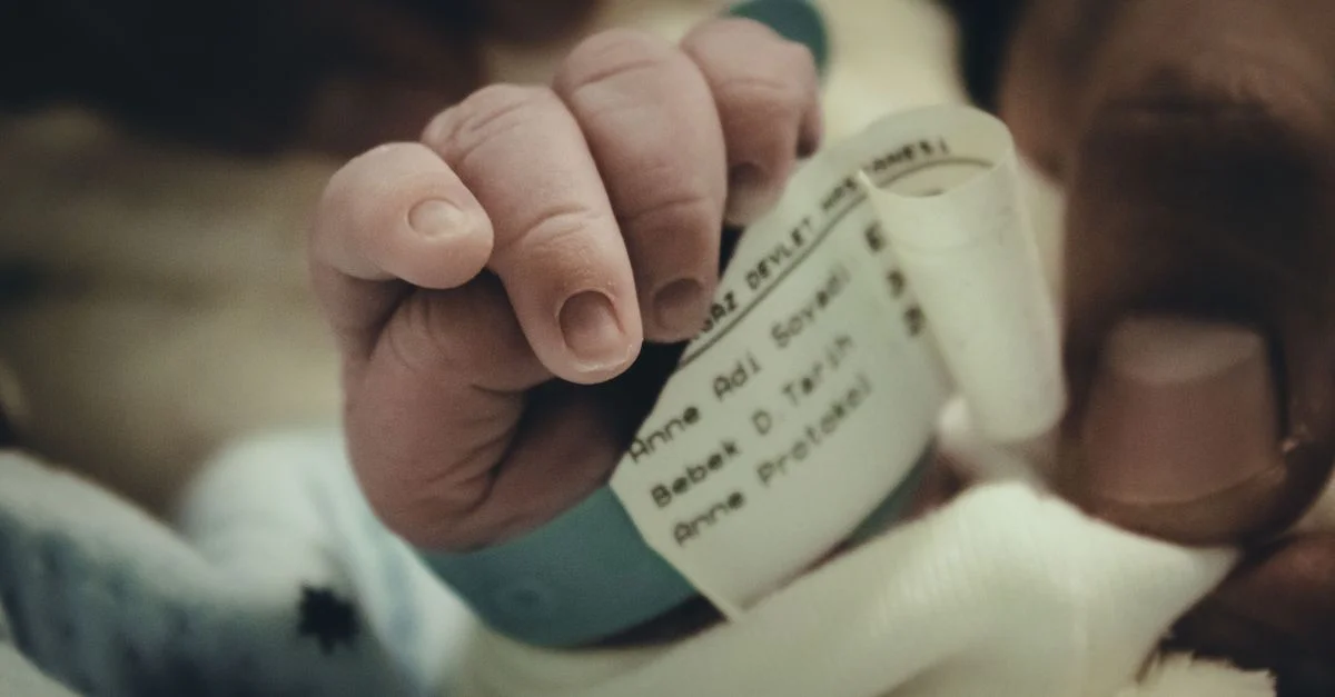 Gros plan sur la main d'un bébé nouveau-né avec un bracelet d'hôpital, symbolisant la nouvelle vie et les soins.