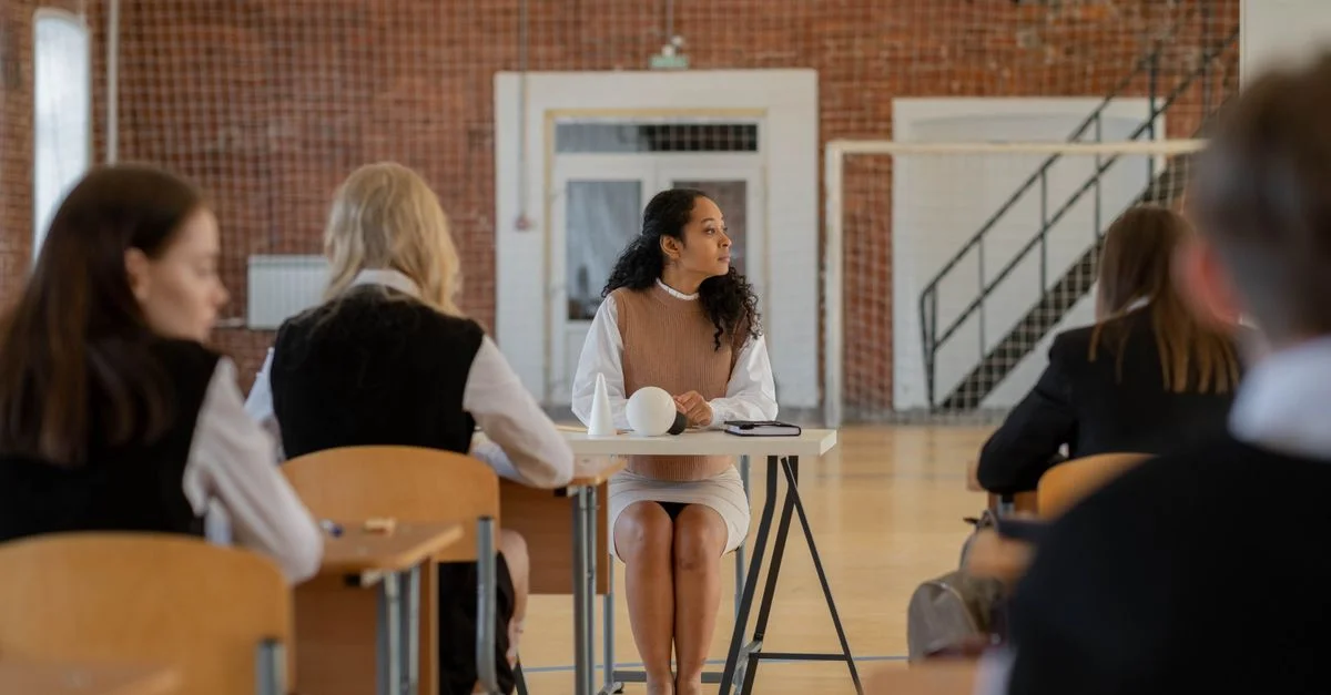 Enseignante assise à son bureau pendant un cours dans un gymnase scolaire.